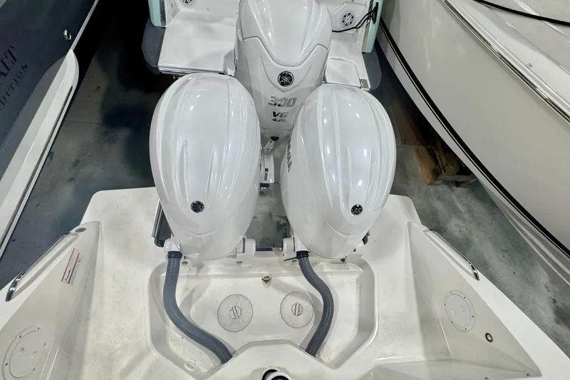 Slide: The Image of 2024 Pursuit DC 266 Dual Console with twin Yamaha outboard engines in a showroom. - 2