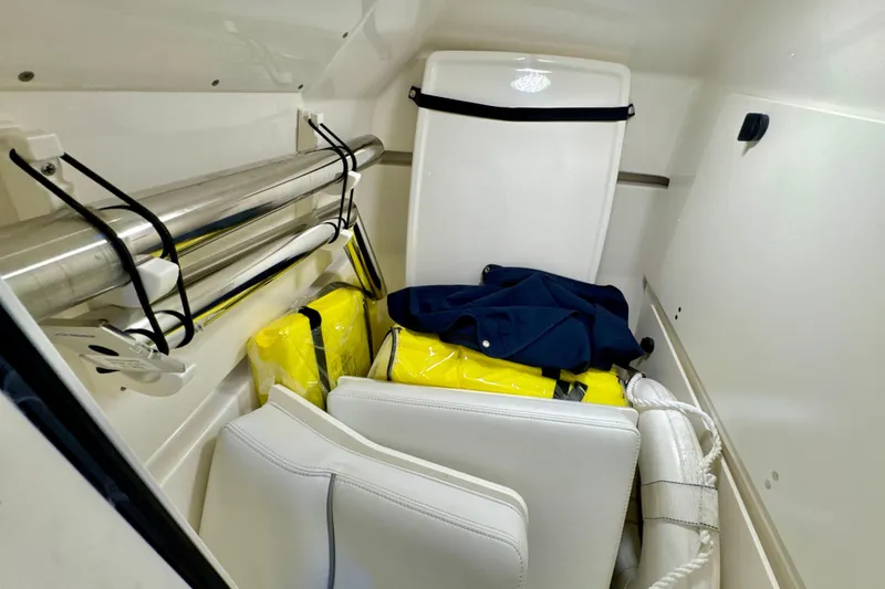 Slide: The Image of 2024 Pursuit DC 266 Dual Console storage area with life jackets and cushions. - 24
