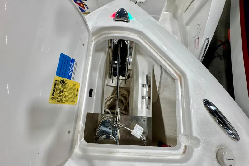 Slide: The Image of 2024 Pursuit DC 266 Dual Console anchor compartment with warning labels and rope storage. - 28