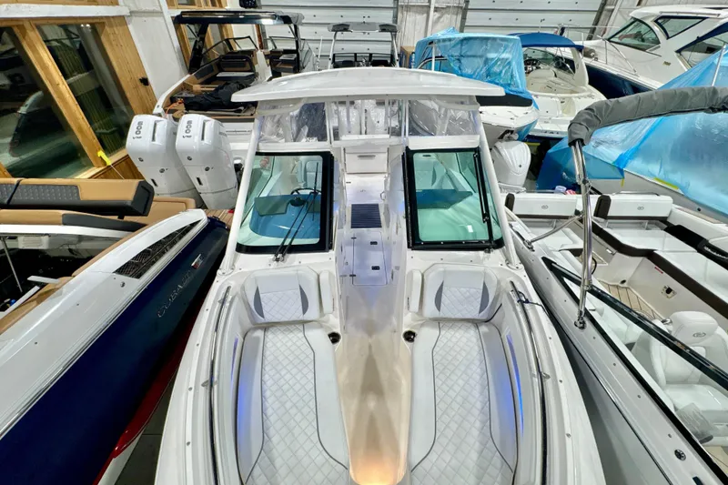 Slide: The Image of 2024 Pursuit DC 266 Dual Console boat in showroom, featuring sleek design and twin engines. - 32