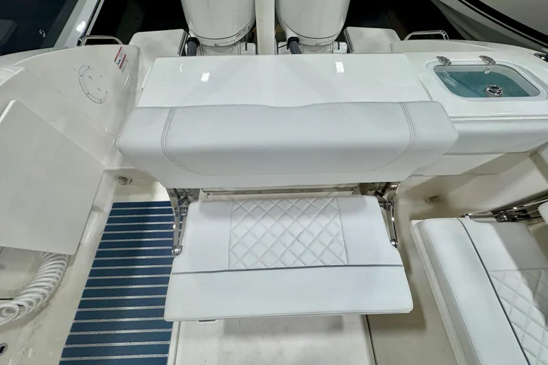 Slide: The Image of 2024 Pursuit DC 266 Dual Console boat interior with white seating and blue-striped flooring. - 8