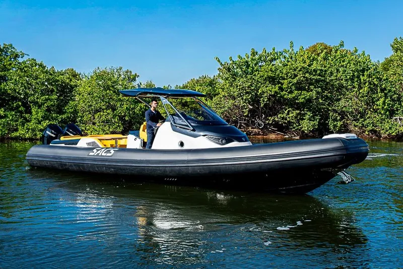 Slide: The Image of 2025 SACS Strider 11 boat cruising on a sunny day near lush greenery. - 6