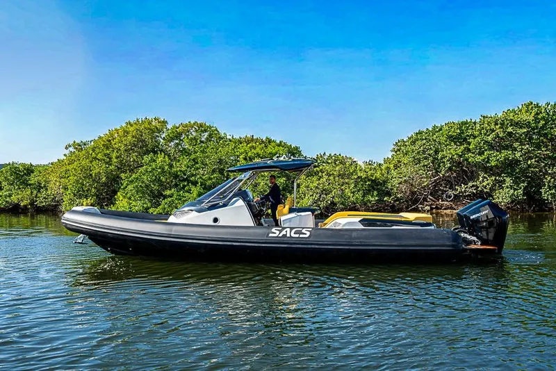 The Image of 2025 SACS Strider 11 boat on calm water, surrounded by lush greenery. - 1