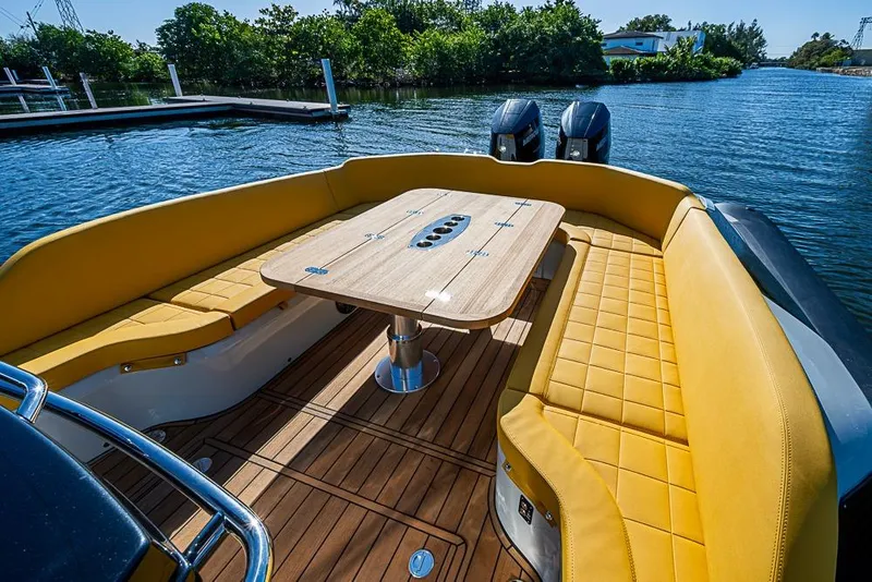 Slide: The Image of 2025 SACS Strider 11 boat with yellow seating and wooden deck, docked by the water. - 25