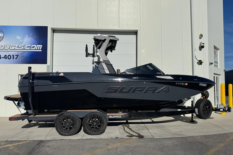The Image of 2024 Supra SL 575 boat on trailer, parked outside a building. - 0