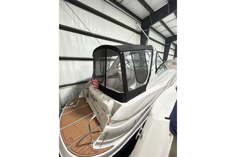 Slide: The Image of 2008 Four Winns 338 Vista boat in storage, featuring a covered cockpit and American flag. - 4