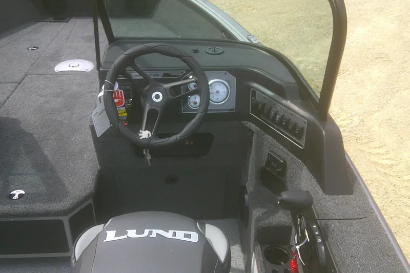 Slide: The Image of 2026 Lund 1875 Impact XS Sport boat interior with steering wheel and control panel. - 11