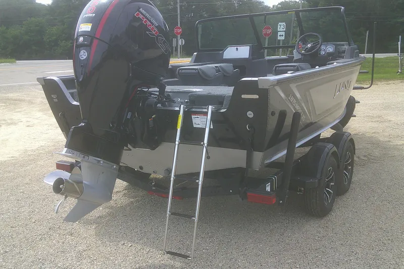 Slide: The Image of 2026 Lund 1875 Impact XS Sport boat with Mercury engine, parked on gravel. - 18
