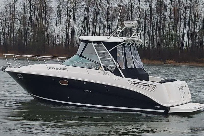 Slide: The Image of 2009 Sea Ray 290 Amberjack boat on calm water with forested background. - 10