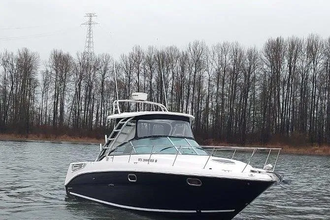 Slide: The Image of 2009 Sea Ray 290 Amberjack boat on a calm river with trees in the background. - 16