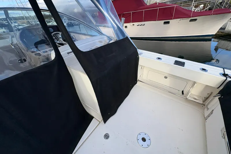 Slide: The Image of 2009 Sea Ray 290 Amberjack boat interior with black cover and docked vessel in background. - 35
