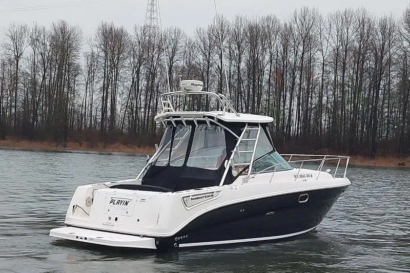 Slide: The Image of 2009 Sea Ray 290 Amberjack boat on a calm river with trees in the background. - 7