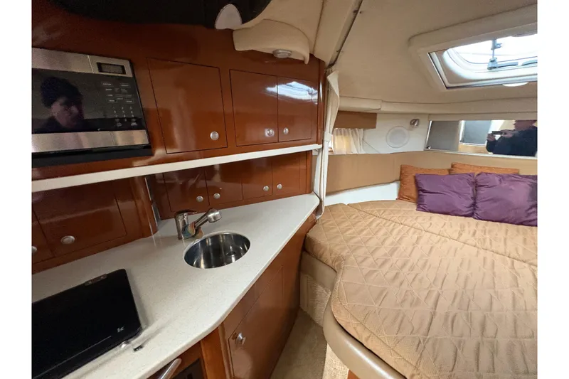 Slide: The Image of 2009 Sea Ray 290 Amberjack cabin interior with kitchenette and cozy sleeping area. - 70