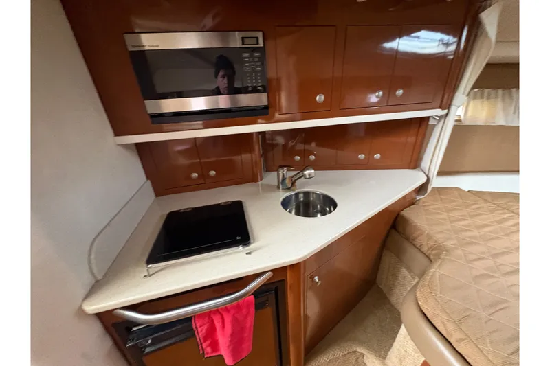 Slide: The Image of 2009 Sea Ray 290 Amberjack cabin kitchen with microwave, sink, and storage cabinets. - 71