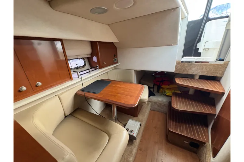 Slide: The Image of 2009 Sea Ray 290 Amberjack cabin interior with seating, table, and wooden steps. - 77