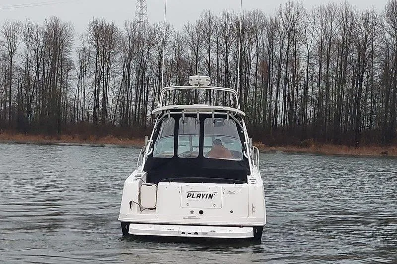 Slide: The Image of 2009 Sea Ray 290 Amberjack boat on a calm river, surrounded by bare trees. - 8