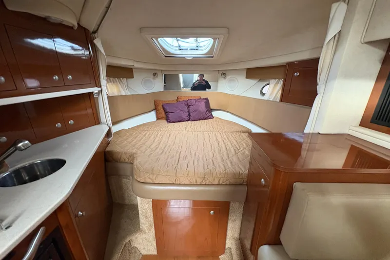 Slide: The Image of 2009 Sea Ray 290 Amberjack cabin interior with bed, sink, and wooden cabinetry. - 88