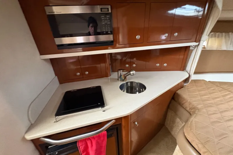 Slide: The Image of 2009 Sea Ray 290 Amberjack interior with kitchenette, featuring microwave, sink, and storage cabinets. - 91