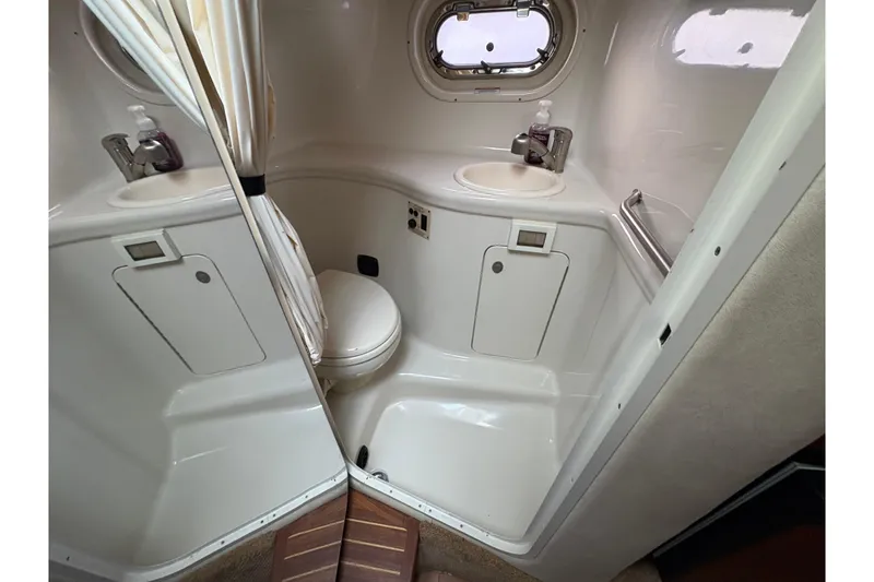 Slide: The Image of 2009 Sea Ray 290 Amberjack bathroom with sink, toilet, and porthole window. - 92