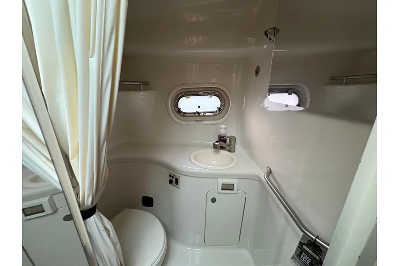 Slide: The Image of 2009 Sea Ray 290 Amberjack boat bathroom with sink, toilet, and porthole window. - 93