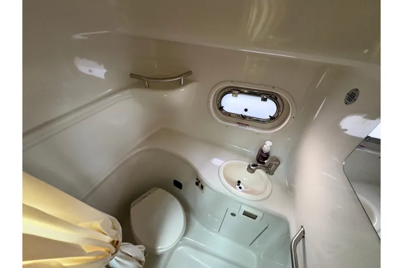 Slide: The Image of 2009 Sea Ray 290 Amberjack bathroom with toilet, sink, and porthole window. - 95