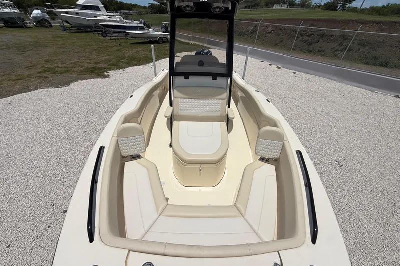 Slide: The Image of 2026 Scout 220 XSF boat interior with beige seating, parked on gravel near other boats. - 20