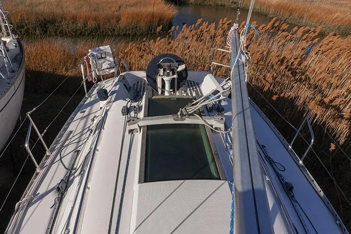 Slide: The Image of 1991 Beneteau First 310 sailboat deck with rigging, surrounded by tall reeds. - 10