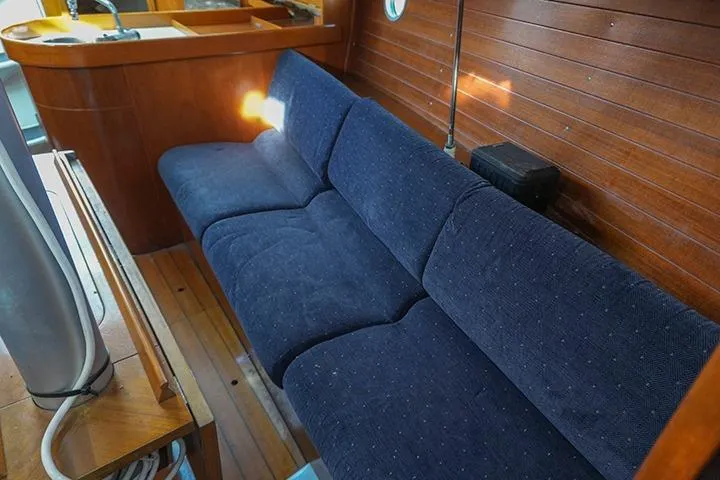 Slide: The Image of Interior of 1991 Beneteau First 310 sailboat with blue sofa and wooden paneling. - 25