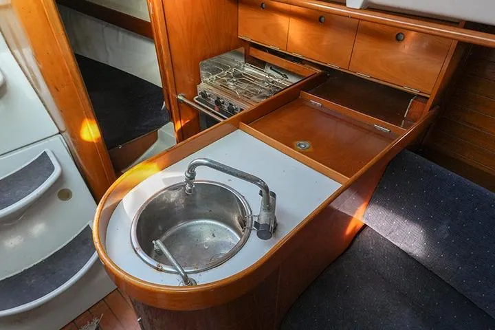 Slide: The Image of 1991 Beneteau First 310 yacht interior with compact kitchen sink and stove. - 26
