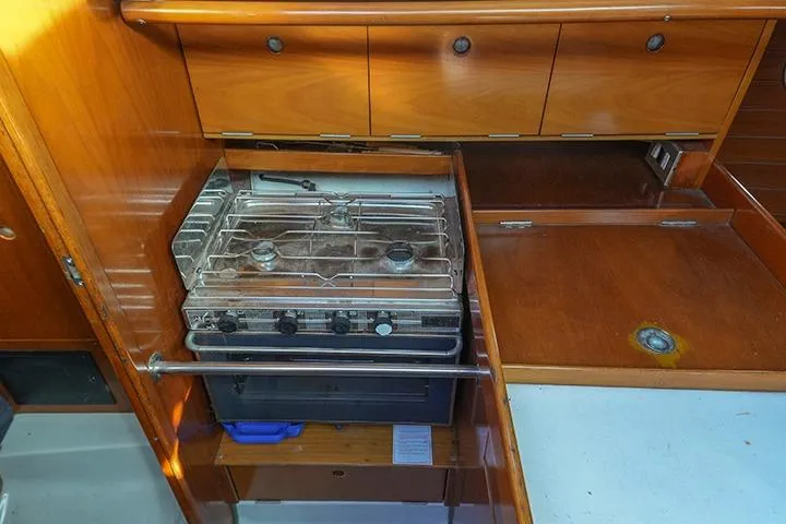 Slide: The Image of 1991 Beneteau First 310 yacht kitchen with stove and wooden cabinetry. - 27