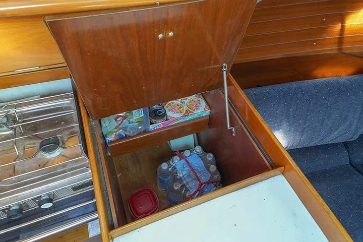 Slide: The Image of Storage compartment in 1991 Beneteau First 310 yacht, containing water bottles and food items. - 28