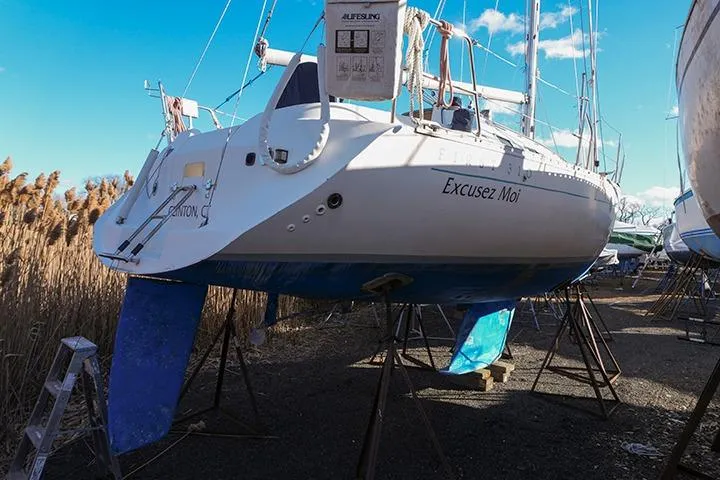 Slide: The Image of 1991 Beneteau First 310 sailboat on stands, named "Excusez Moi," under clear blue sky. - 4