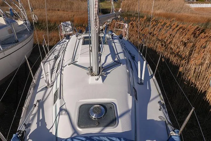 Slide: The Image of 1991 Beneteau First 310 sailboat deck view, surrounded by tall reeds. - 9