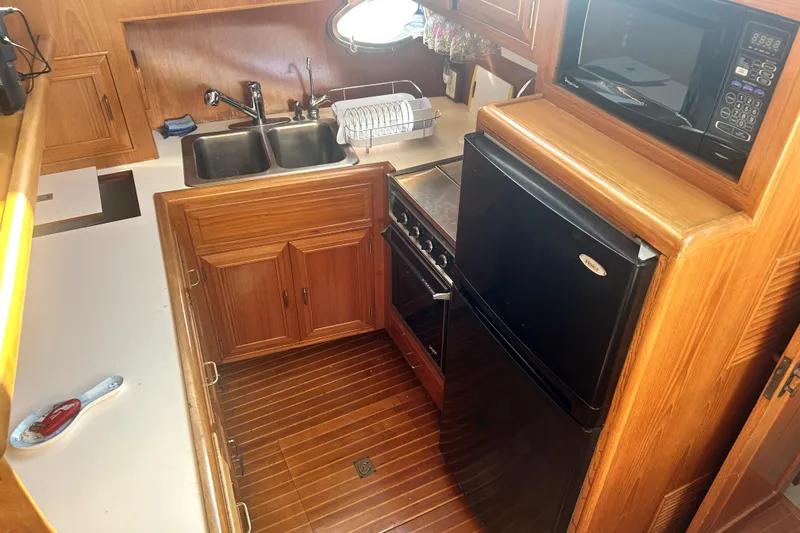 Slide: The Image of 1989 Ocean Alexander 44 CPMY yacht kitchen with wood cabinetry, sink, stove, and microwave. - 20