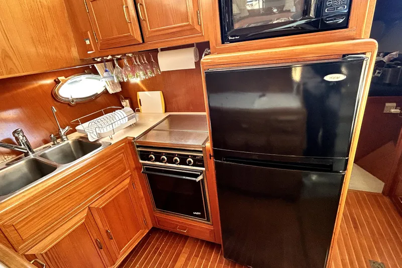 Slide: The Image of 1989 Ocean Alexander 44 CPMY yacht kitchen with wood cabinetry, black appliances, and double sink. - 19