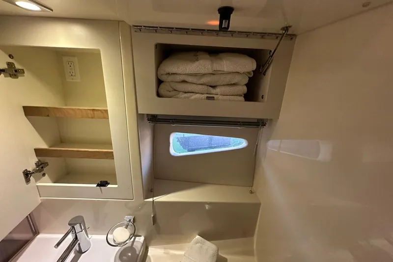 Slide: The Image of Interior of 2014 Sea Ray 410 Sundancer bathroom with towels and storage shelves. - 42