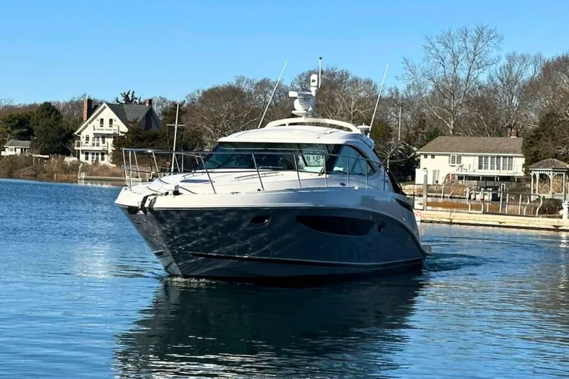Slide: The Image of 2014 Sea Ray 410 Sundancer yacht on calm water near residential area. - 5
