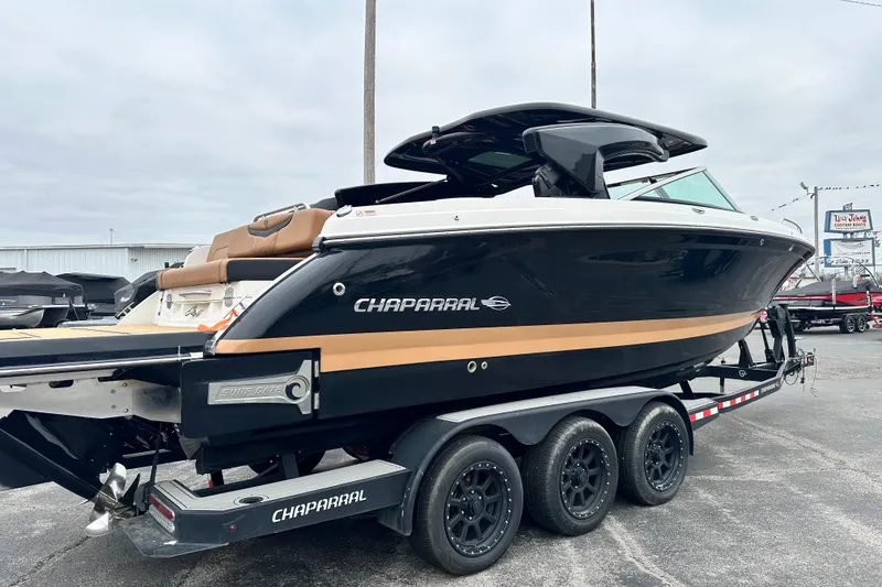 Slide: The Image of 2023 Chaparral 30 Surf boat on trailer, sleek design, black and tan color scheme. - 4