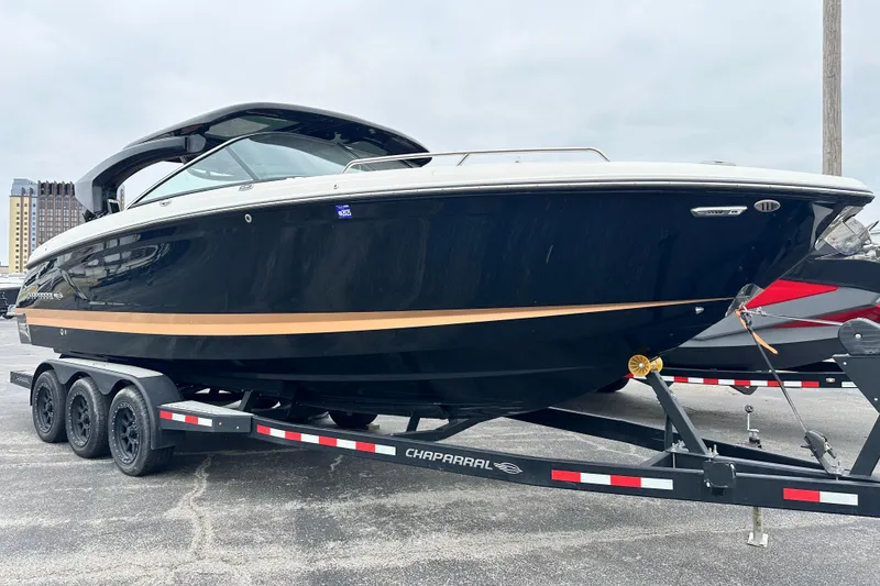 Slide: The Image of 2023 Chaparral 30 Surf boat on a trailer, sleek design, black and gold accents. - 5