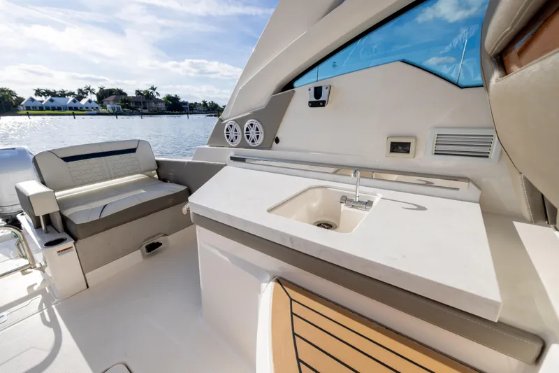 Slide: The Image of 2022 Tiara 34 LX boat interior with seating and sink, overlooking waterfront homes. - 12