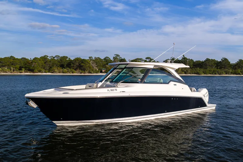 Slide: The Image of 2022 Tiara 34 LX boat on calm water with scenic forest backdrop. - 39