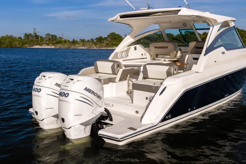 Slide: The Image of 2022 Tiara 34 LX boat with dual Mercury 400 engines on a calm lake. - 4