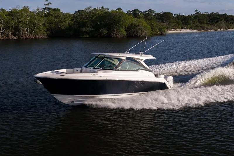 Slide: The Image of 2022 Tiara 34 LX boat cruising on a scenic river with lush greenery. - 47