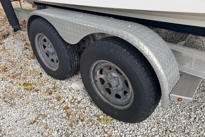 Slide: The Image of Trailer wheels of 2021 Robalo R230 Center Console on gravel surface. - 26