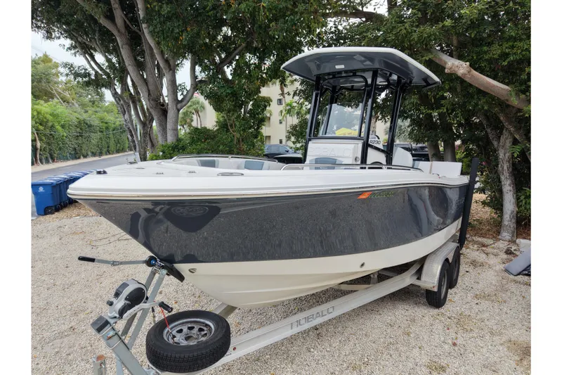 Slide: The Image of 2021 Robalo R230 Center Console boat on trailer, parked under trees. - 4