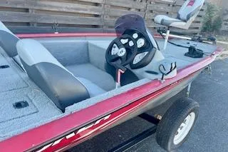 Slide: The Image of 2013 Tracker Pro Team 175 TXW boat, red exterior, steering wheel, and seating, parked on a trailer. - 9