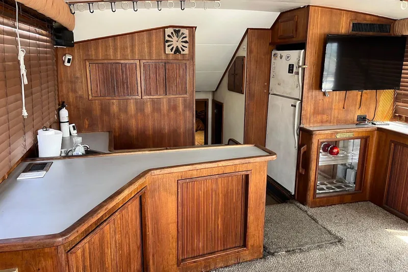 Slide: The Image of 1989 Topaz 44 Sportfisherman interior with wood paneling, kitchenette, and TV. - 12