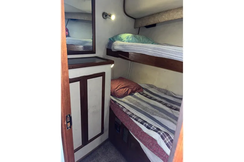 Slide: The Image of Cozy bunk beds in 1989 Topaz 44 Sportfisherman cabin, featuring striped bedding and wooden accents. - 17
