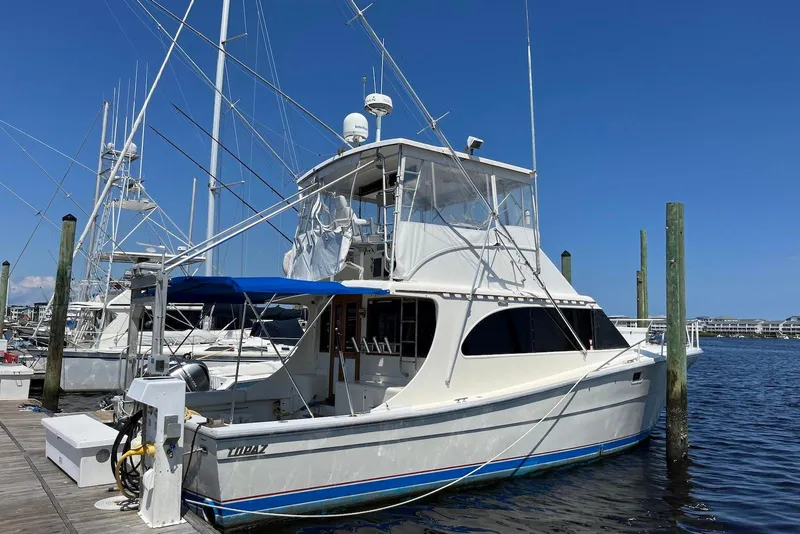 Slide: The Image of 1989 Topaz 44 Sportfisherman docked, featuring fishing rods and blue canopy. - 2