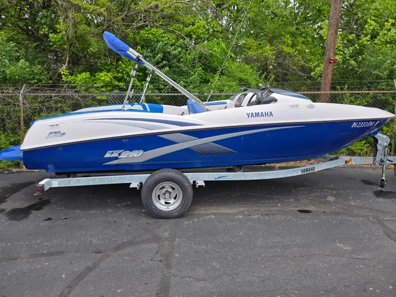 The Image of 2004 Yamaha Boats 210 LX on trailer, blue and white design, parked outdoors. - 0